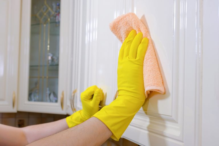 A man wipes the dust from the furniture with a rag in the kitchen. House cleaning